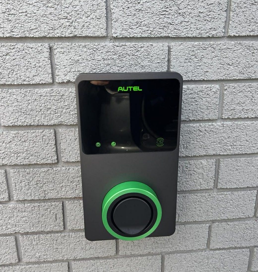 Autel EV charger installed on a textured brick exterior wall in Newcastle by Nate's Rates Electrical